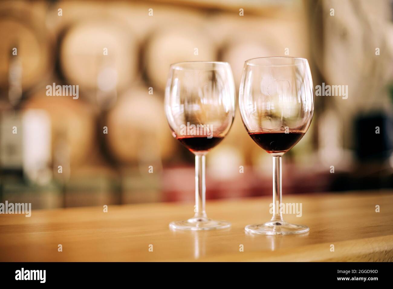 Due bicchieri di vino rosso su tavola in legno in cantina Foto Stock