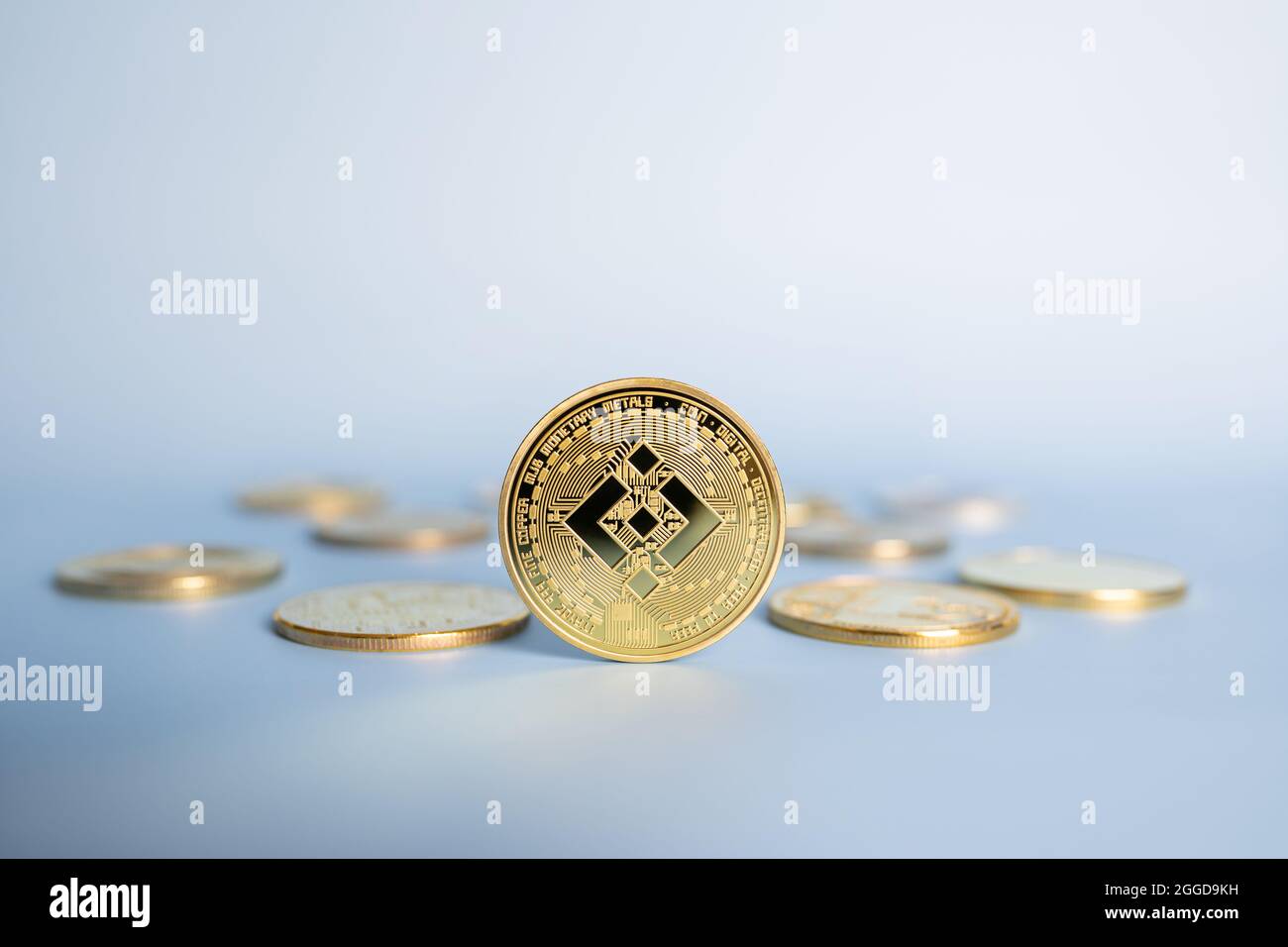 Binance BNB Cryptocurrency moneta in piedi in posizione centrale tra mazzo di cripto monete d'oro su sfondo blu. Primo piano, messa a fuoco morbida. Foto Stock