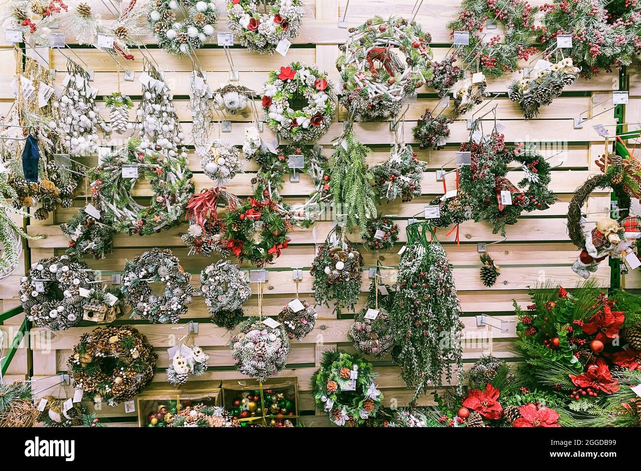 Varietà di decorazioni colorate su ripiani in legno di un grande negozio. Giocattoli artificiali di Natale per decorazione preparati per la vendita al supermercato. Foto Stock