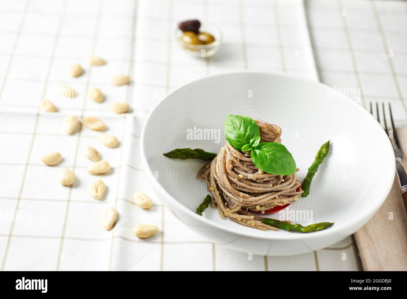Spaghetti di grano integrale con pesto di oliva e mandorla, decorati con asparagi Foto Stock