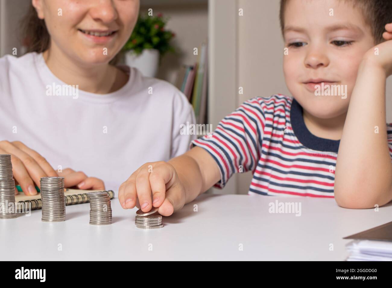 Il genitore insegna al bambino come maneggiare i soldi. Corso di alfabetizzazione finanziaria per bambini in età prescolare e scolastica. Foto Stock