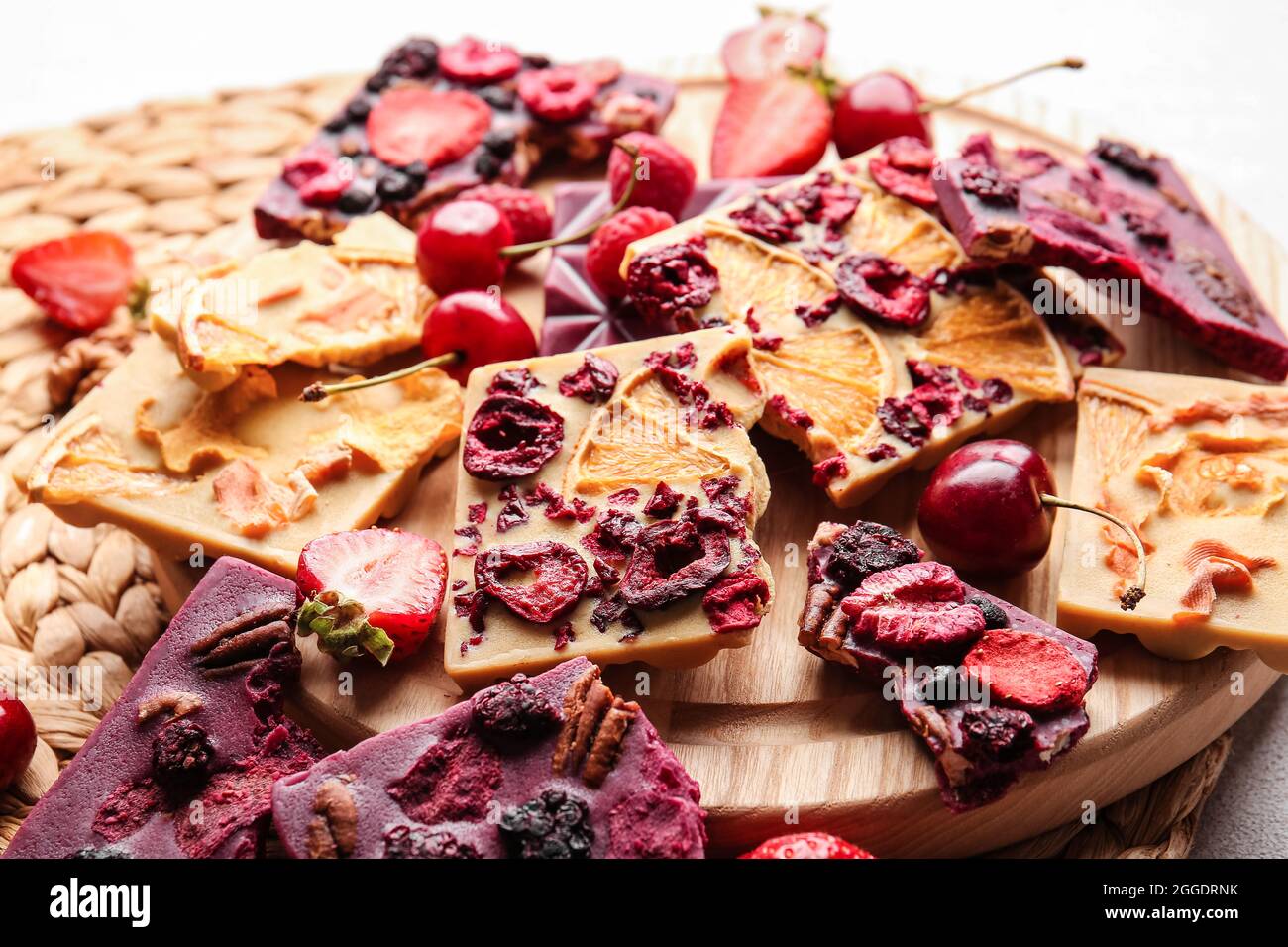 Tavolette di cioccolato fatte a mano con frutta, frutti di bosco e noci su sfondo chiaro Foto Stock