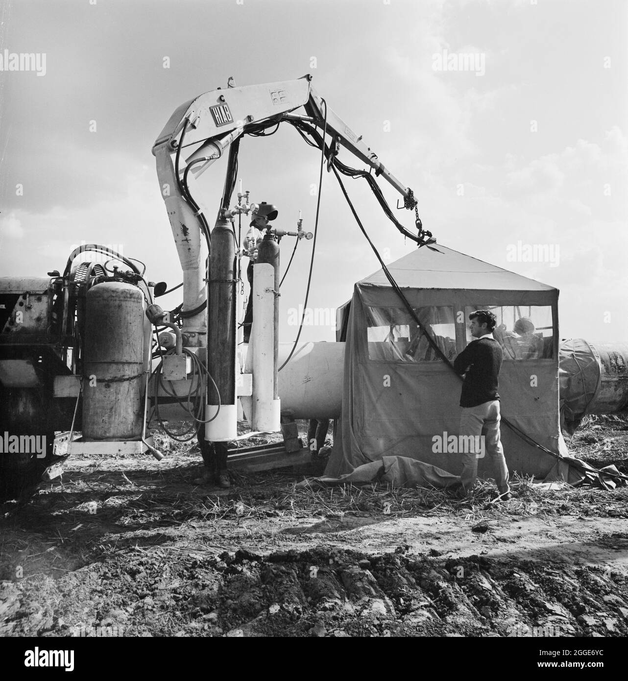 Una vista della saldatura che avviene lungo il gasdotto Fens, che mostra una copertura protettiva eretta per coprire due sezioni di tubo che vengono saldate insieme. I lavori per la posa del gasdotto Fens sono iniziati nel giugno 1967 e sono stati una joint venture tra Laing Civil Engineering e le società francesi Entrepose e Grands Travaux de Marseille (GTM) per il Consiglio del gas. Oltre 600 uomini hanno lavorato al progetto per posare tubi in acciaio di diametro 36 pollici a partire da West Winch a Norfolk e fino a dove si è collegato con il prossimo contratto a Woodcroft Castle a Cambridgeshire. Il gasdotto attraversava quattro fiumi e numerosi Foto Stock