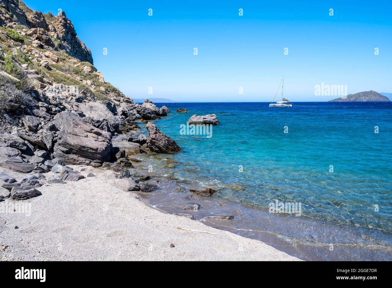 Spiaggia a Gyali, barca a vela alle spalle, Dodecaneso, Grecia Foto Stock