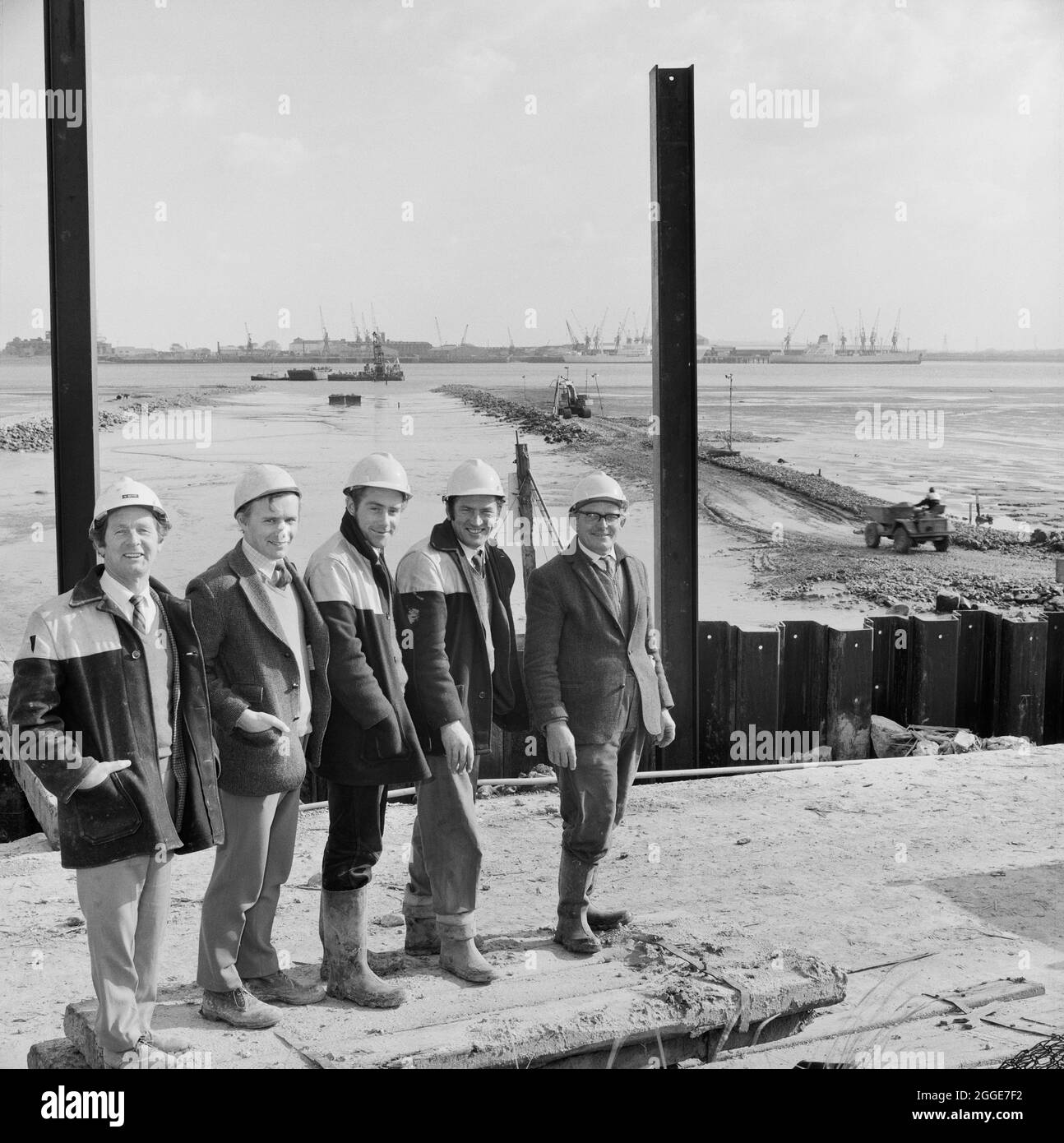 Un ritratto di gruppo della "squadra di fuorilegge" presso la centrale elettrica dell'Isola di Grain, che mostra il canale di discesa nel fiume Medway in costruzione sullo sfondo. Questa immagine è stata pubblicata nell'edizione di novembre 1973 della newsletter mensile di Laing; Team Spirit. Foto Stock