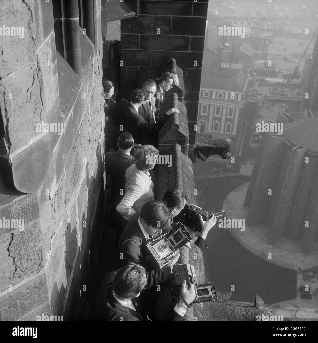 Un gruppo di persone con telecamere, probabilmente membri della stampa, che si erge sulla torre della Chiesa in rovina della Cattedrale di San Michele, durante l'operazione di abbassare la guglia in bronzo da 80 piedi sul tetto della nuova Cattedrale di Coventry. La fotografia è stata scattata durante l'operazione Rich Man, un progetto congiunto che coinvolse il personale dell'Aeronautica reale e il personale di Laing. Questo ha coinvolto un elicottero belvedere RAF che si è issato per posizionare la guglia di bronzo da 80 piedi sulla nuova cattedrale. La parte dell'operazione di abbassamento della traversa di 1/2 tonnellate che si trova sulla sommità della guglia doveva essere posticipata a causa delle condizioni di vento. Foto Stock