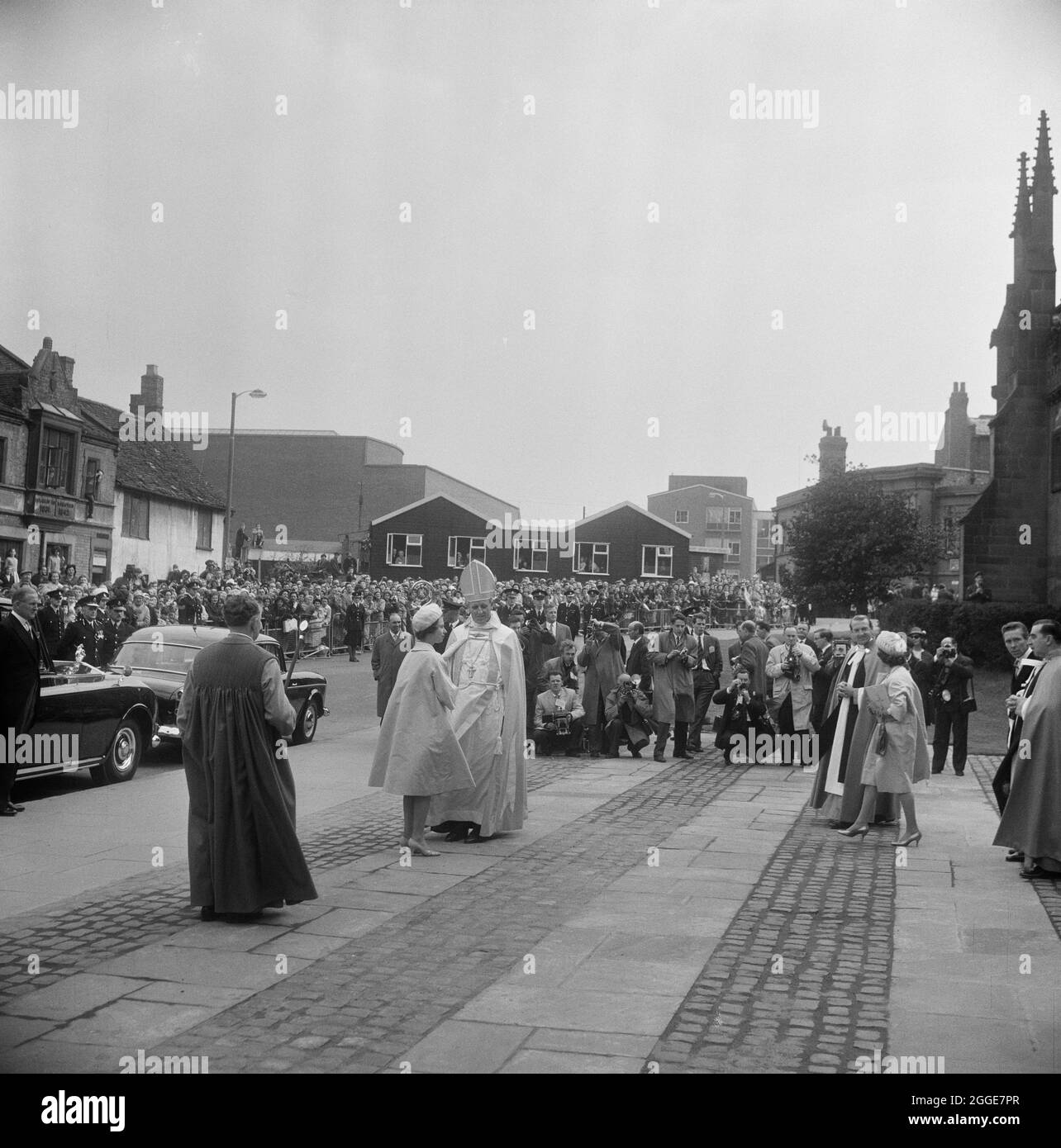 Una veduta della Regina Elisabetta II e del Vescovo di Coventry sul marciapiede fuori dalla Cattedrale di Coventry il giorno del servizio di consacrazione, con fotografi della stampa e folle che guardano dallo sfondo. Questa immagine è stata catalogata come parte del Breaking New Ground Project in collaborazione con il John Laing Charitable Trust nel 2019-20. Foto Stock