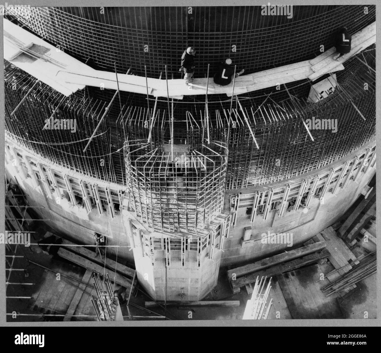 Guardando verso il basso il lato est del reattore n°1 durante la costruzione della centrale nucleare di Berkeley, mostrando lo scudo biologico e il suo albero di scarico con un team di Laing che lavora sopra. La centrale nucleare di Berkeley è stata la prima centrale nucleare commerciale nel Regno Unito e una delle prime generazioni di reattori nucleari in Gran Bretagna. Aveva due reattori Magnox ed era una delle quattro stazioni situate vicino alla foce del fiume Severn e del canale di Bristol. I Laing sono stati gli ingegneri civili del progetto, con lavori che iniziano il 7 gennaio 1957. La centrale nucleare c Foto Stock Guardando verso il basso il lato est del reattore n°1 durante la costruzione della centrale nucleare di Berkeley, mostrando lo scudo biologico e il suo albero di scarico con un team di Laing che lavora sopra. La centrale nucleare di Berkeley è stata la prima centrale nucleare commerciale nel Regno Unito e una delle prime generazioni di reattori nucleari in Gran Bretagna. Aveva due reattori Magnox ed era una delle quattro stazioni situate vicino alla foce del fiume Severn e del canale di Bristol. I Laing sono stati gli ingegneri civili del progetto, con lavori che iniziano il 7 gennaio 1957. La centrale nucleare c Foto Stock