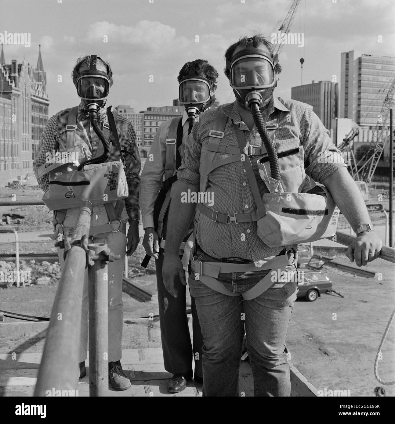 Tre uomini che indossano maschere a gas Draeger durante un corso di sicurezza presso il cantiere della British Library. La British Library è stata progettata dall'architetto Colin St John Wilson ed è stata costruita tra il 1982 e il 1999 dall'appaltatore John Laing Limited. Foto Stock