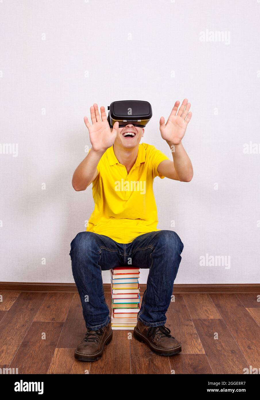 Happy Young Man in Virtual Reality Headset sul pavimento con un libro Foto Stock