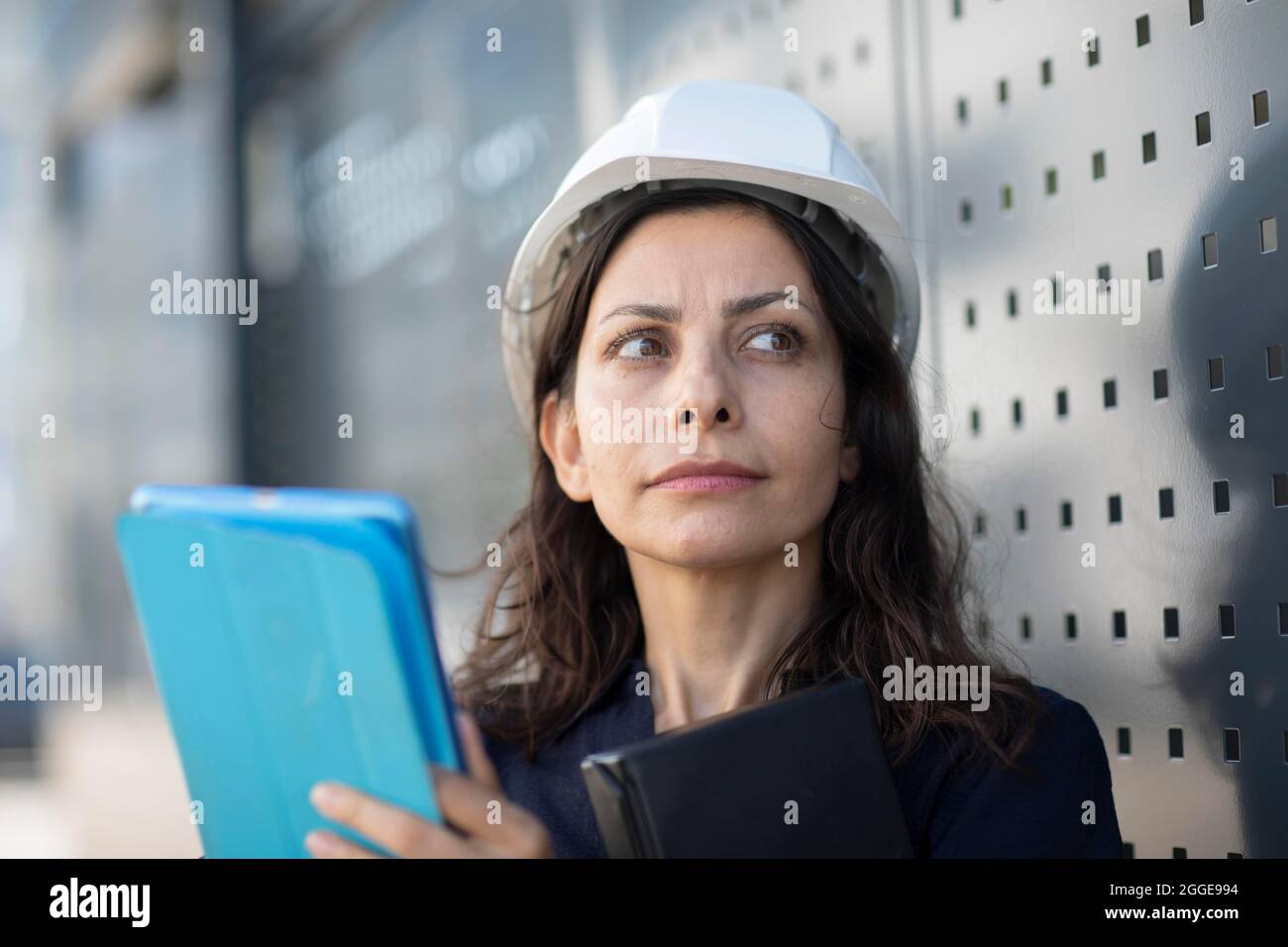 Donna di mezza età con capelli scuri e casco controlla una pianta con una tavoletta, Friburgo, Baden-Wuerttemberg, Germania Foto Stock