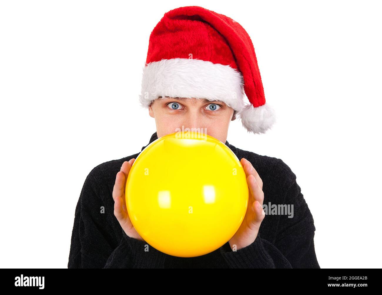 Giovane uomo a Santa Hat gonfiare un palloncino giallo sullo sfondo bianco Foto Stock