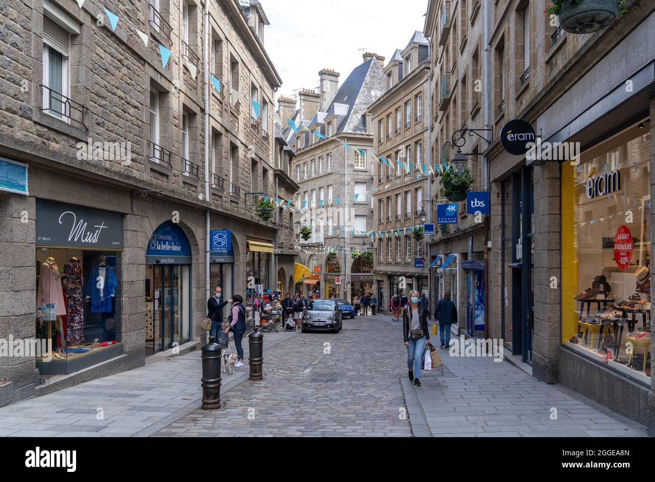 Persone che acquistano con maschere nelle strade vuote della città vecchia di Saint Malo, Bretagna, Francia Foto Stock