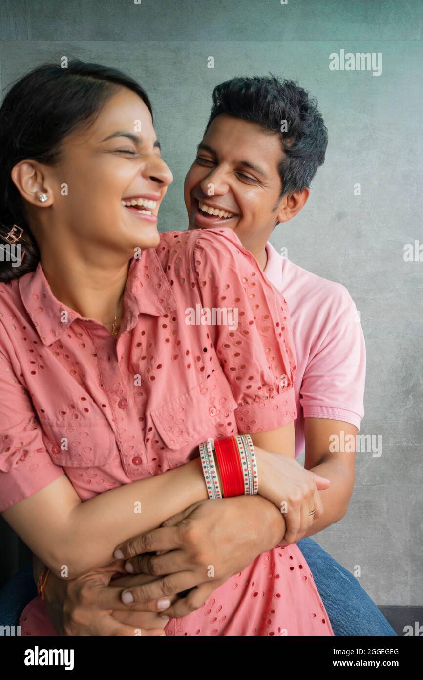 Giovani sposi felici che trascorrono del tempo di qualità mentre la moglie si siede sul braccio del marito. Foto Stock