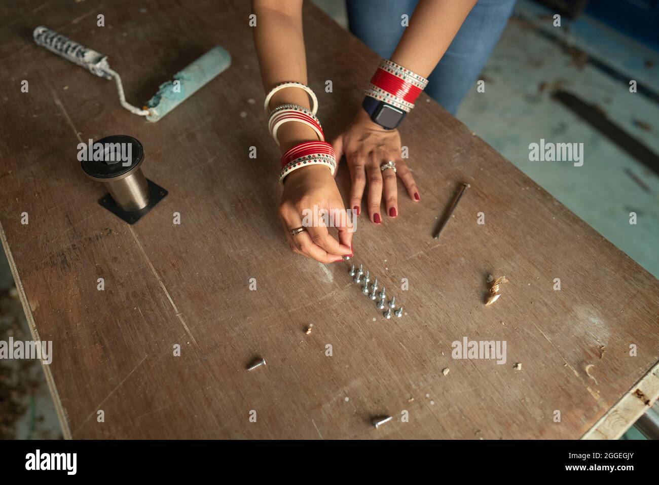 Una donna appena sveglata che monta le viti sul tavolo per il rifacimento della nuova casa. Foto Stock