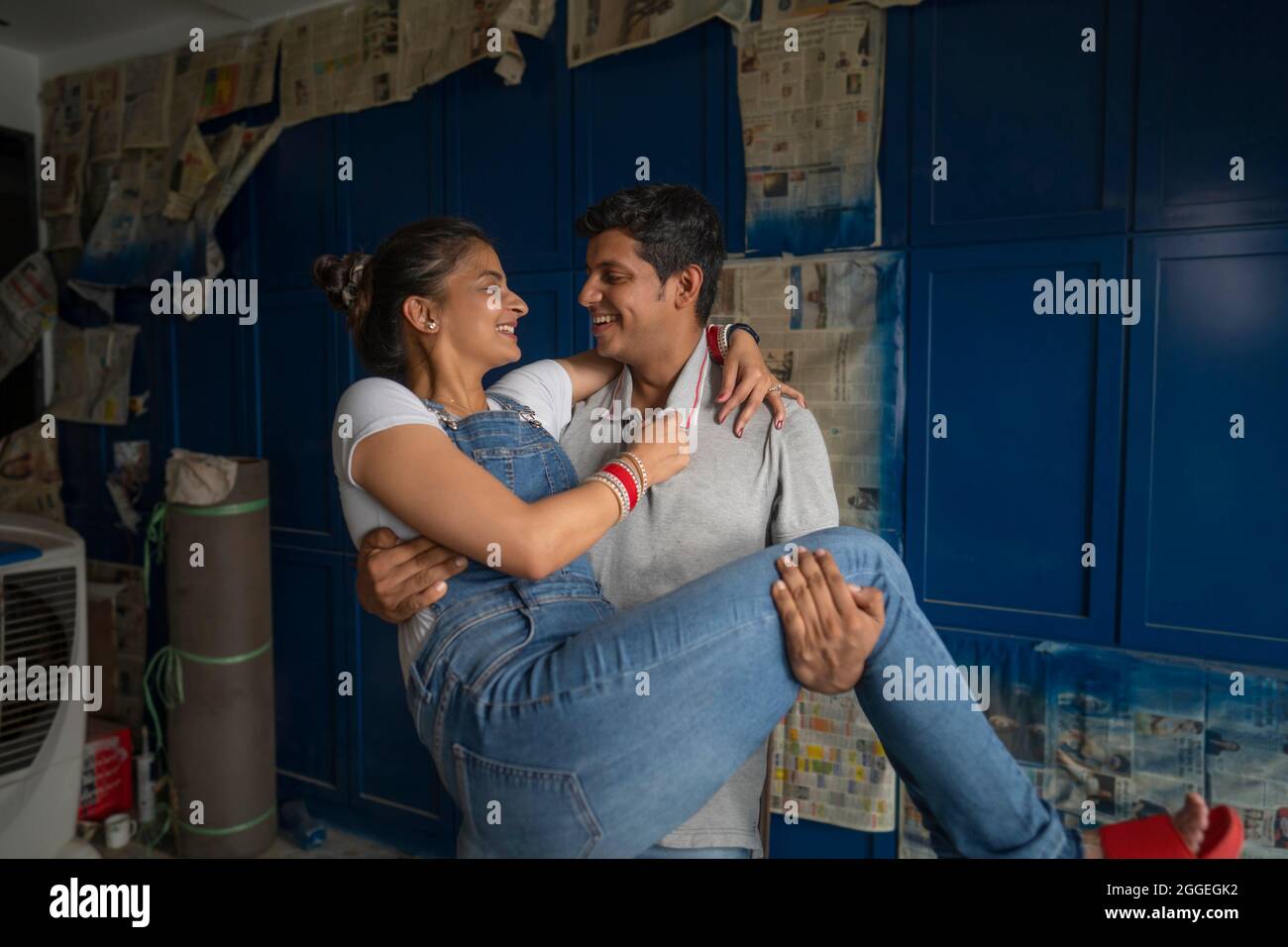 Giovani sposi che condividono un momento romantico con il marito che tiene la moglie tra le braccia. Foto Stock