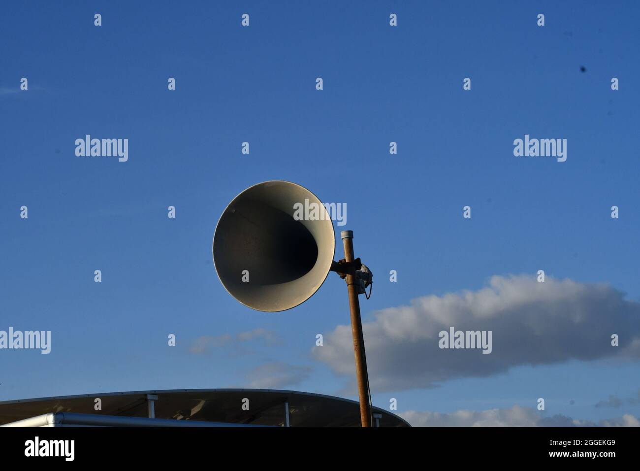 Un vecchio megafone in stile retrò con lo sfondo di un cielo blu con nuvole ombreggiate Foto Stock