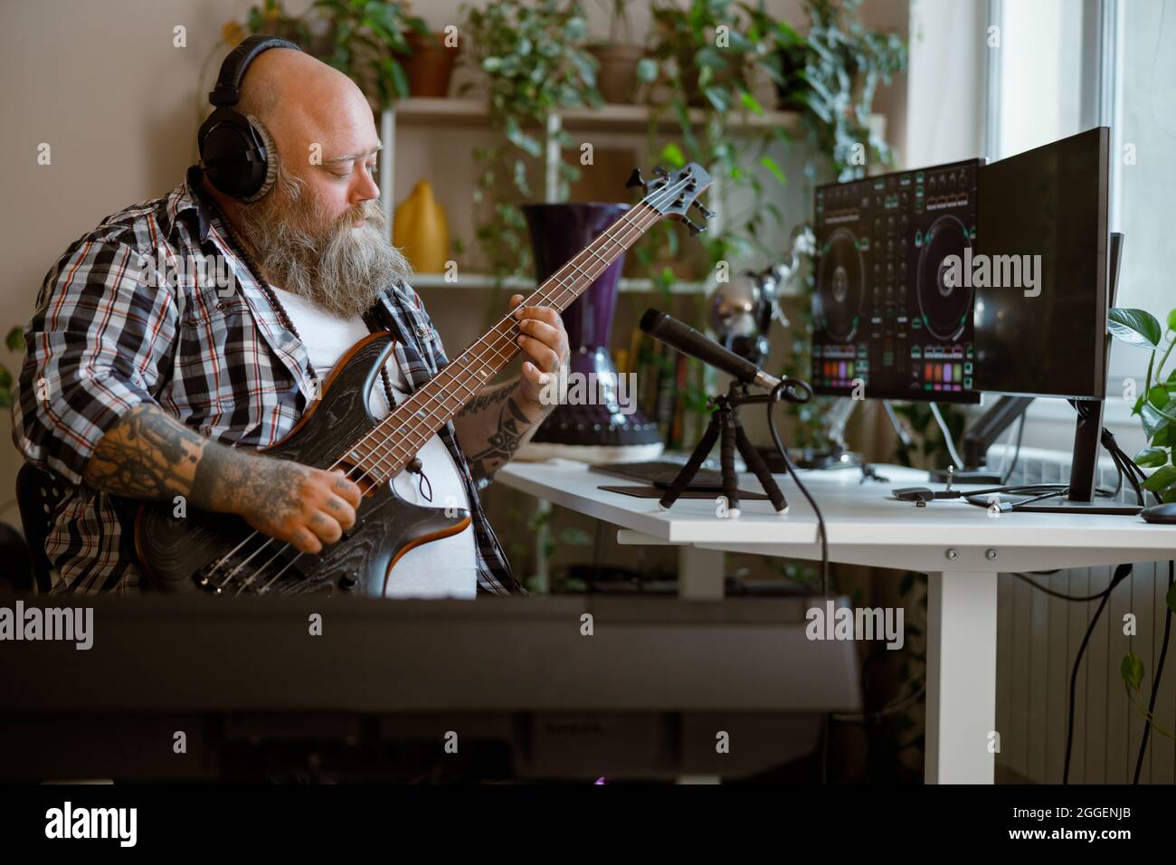 Il musicista concentrato suona la canzone di registrazione della chitarra di basso nello studio domestico Foto Stock