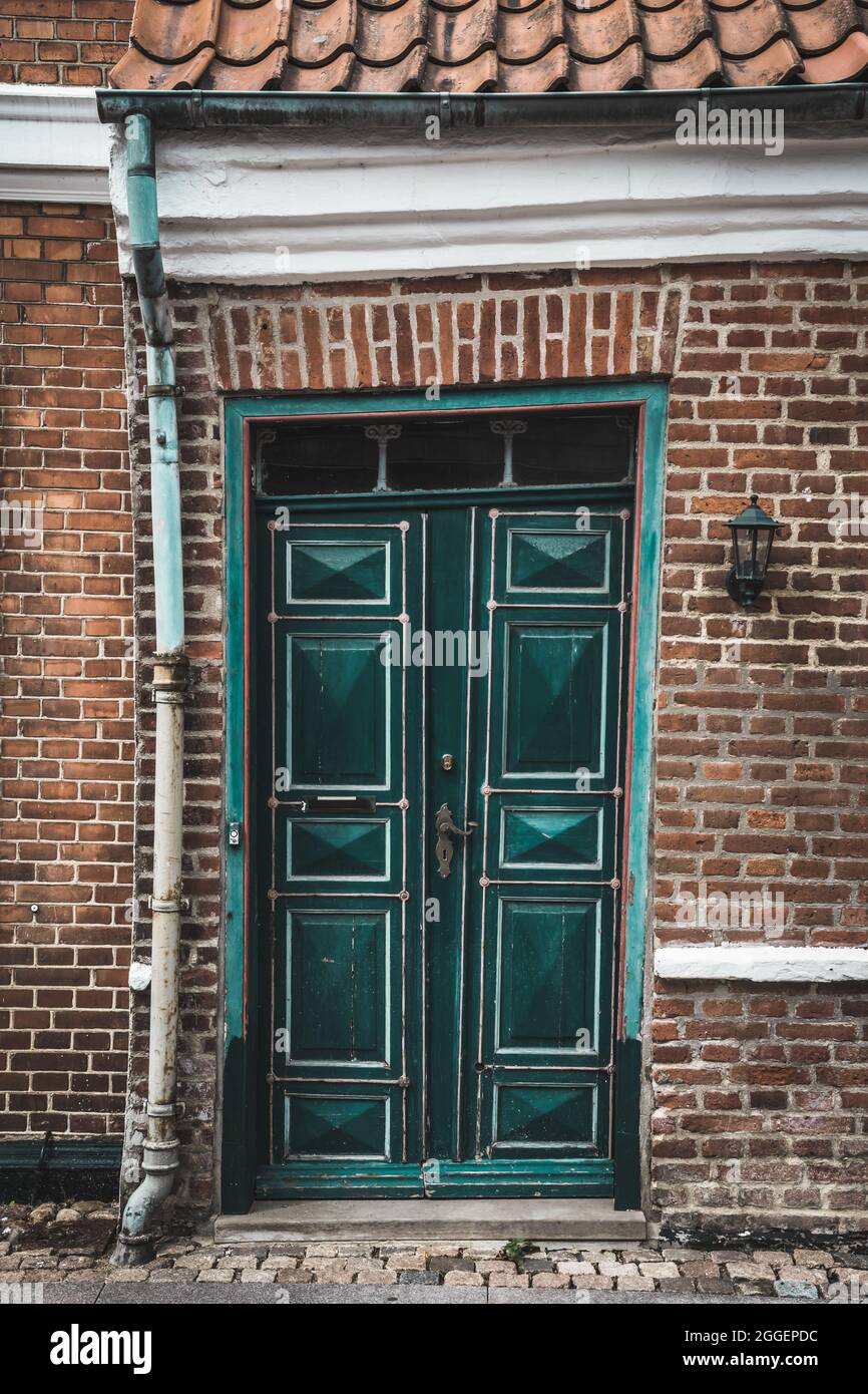 Vecchia porta di legno verdeggiante su un edificio di mattoni Foto Stock