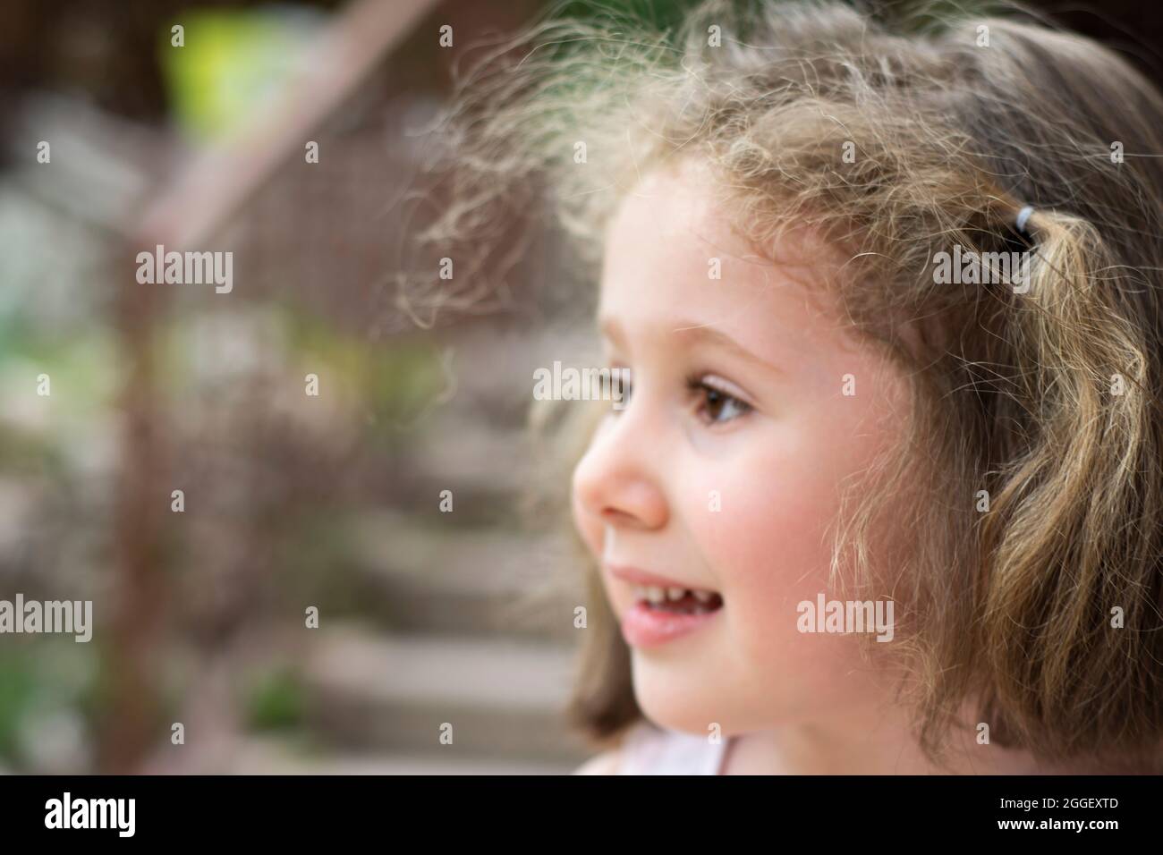 La bambina guarda via con un grande sorriso. Fuoco selettivo Ragazze pulcino Foto Stock