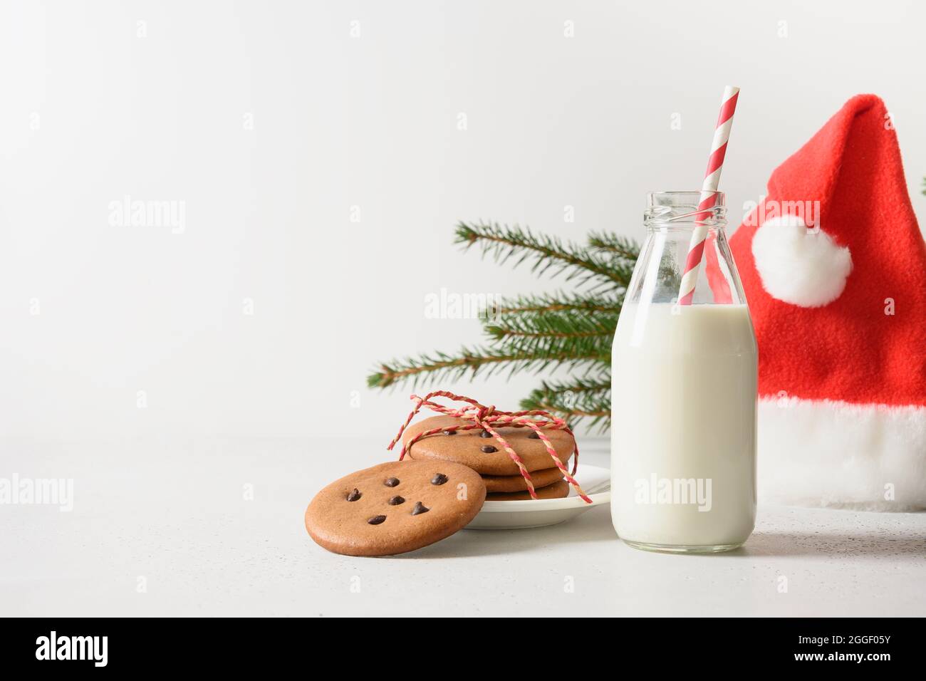 Lettera per Santa, biscotti fatti in casa e latte su bianco. Primo piano. Formato verticale. Foto Stock