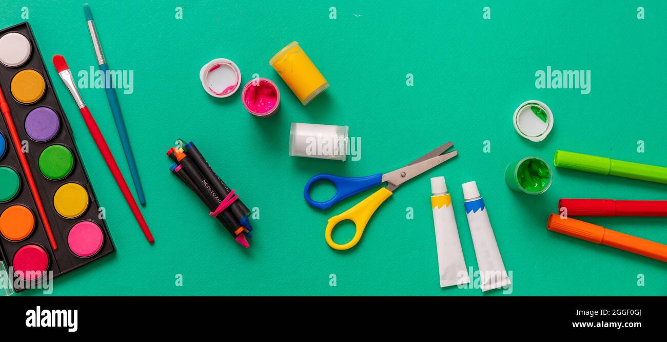 Ragazzi creativi, pittura e disegno. Colori e pennelli colorati su sfondo verde. Istruzione, concetto di ritorno a scuola. Foto Stock