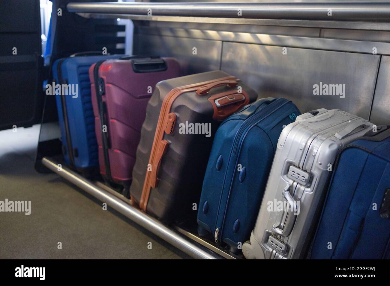 Molti tipi diversi di valigie e bagagli a mano nel bagagliaio del treno. I  bagagli più grandi si tengono nello slot del treno Foto stock - Alamy