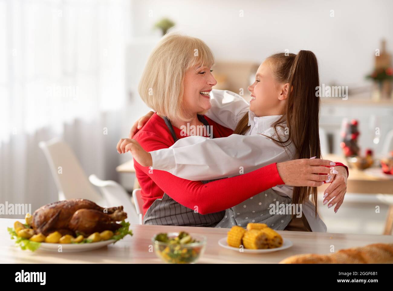 Cucinare con la nonna. Adorabile ragazza con nonna abbracciante mentre prepara il pasto festivo insieme in cucina. Donna anziana e nipote che fanno th Foto Stock