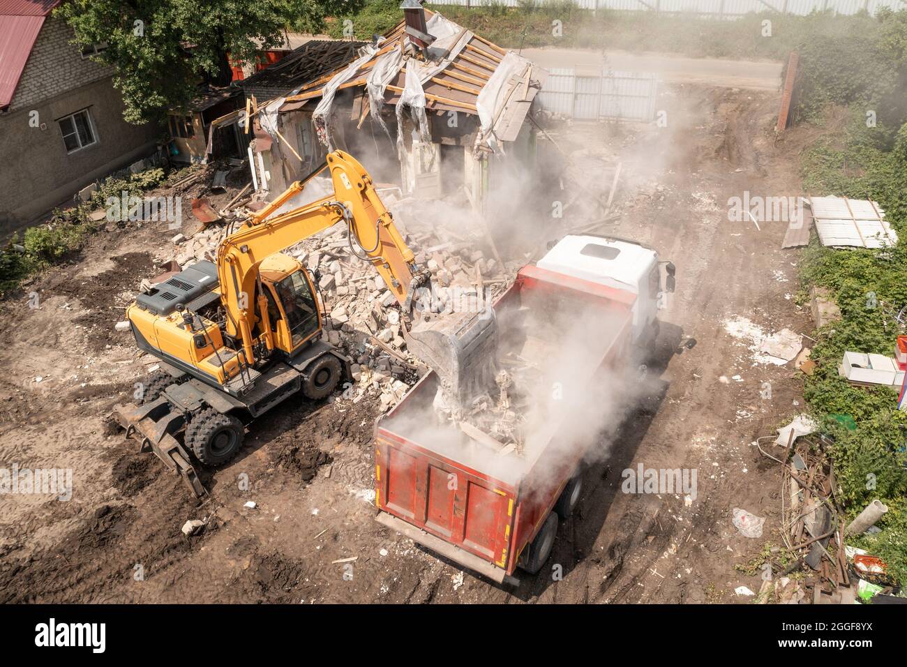 Demolizione di Casa di costruzione per la nuova costruzione. Benna dell'escavatore caricare i rifiuti nel dumper, vista aerea. Foto Stock