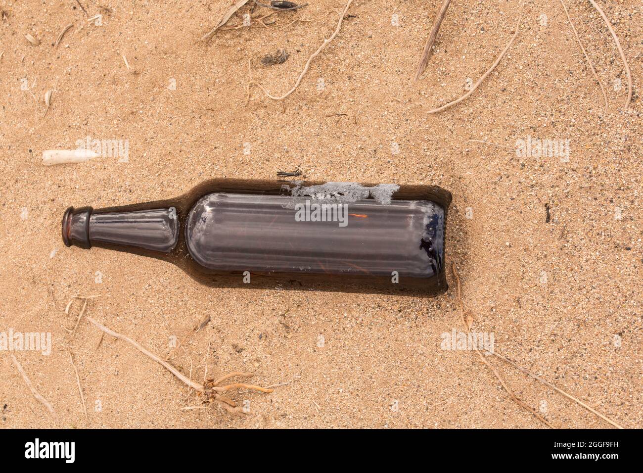 Qualcuno ha lasciato una bottiglia vuota sulla sabbia invece di riciclarla. Foto Stock
