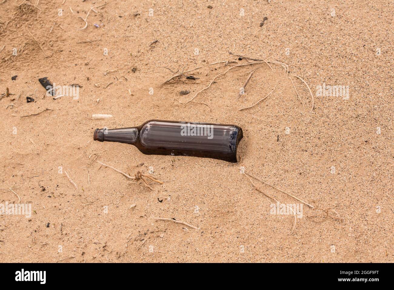 Qualcuno ha lasciato una bottiglia vuota sulla sabbia invece di riciclarla. Foto Stock