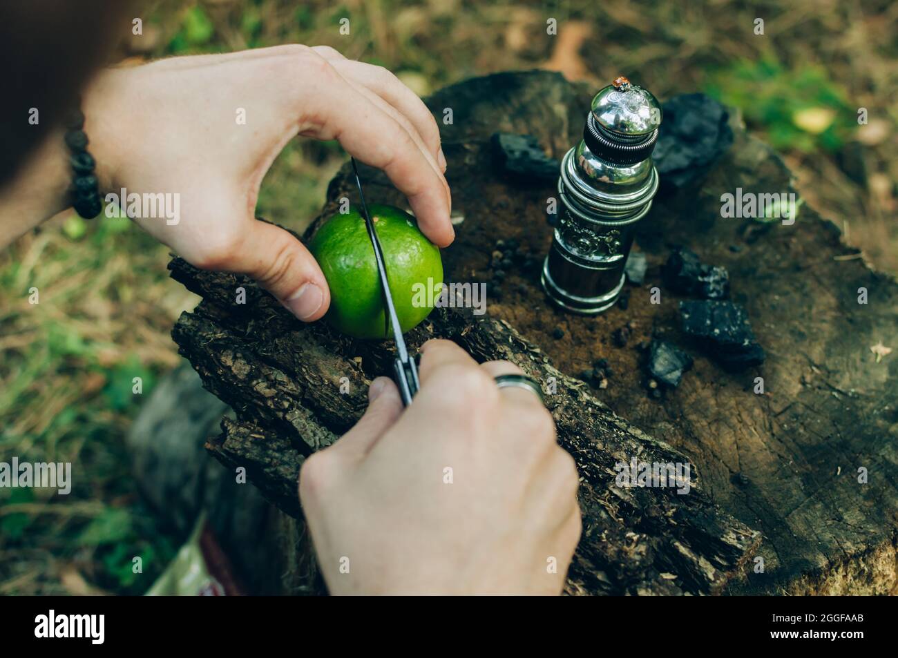 Primo piano di una persona che taglia mandarino con un coltello su una superficie di legno Foto Stock