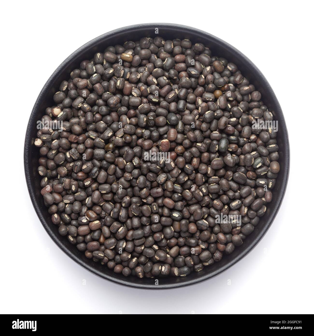 Macro primo piano di gram nero organico (Vigna mungo) o urad nero intero su una ciotola nera di ceramica. Vista dall'alto Foto Stock