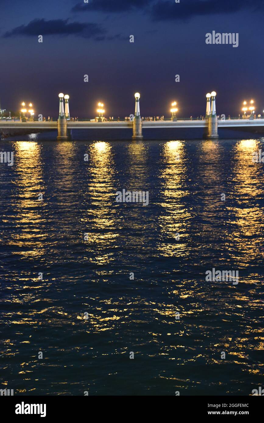San Sebastian, Spagna - 29 ago 2021: Luci dal Ponte Kursal riflettendo sulle acque del fiume Urumea Foto Stock