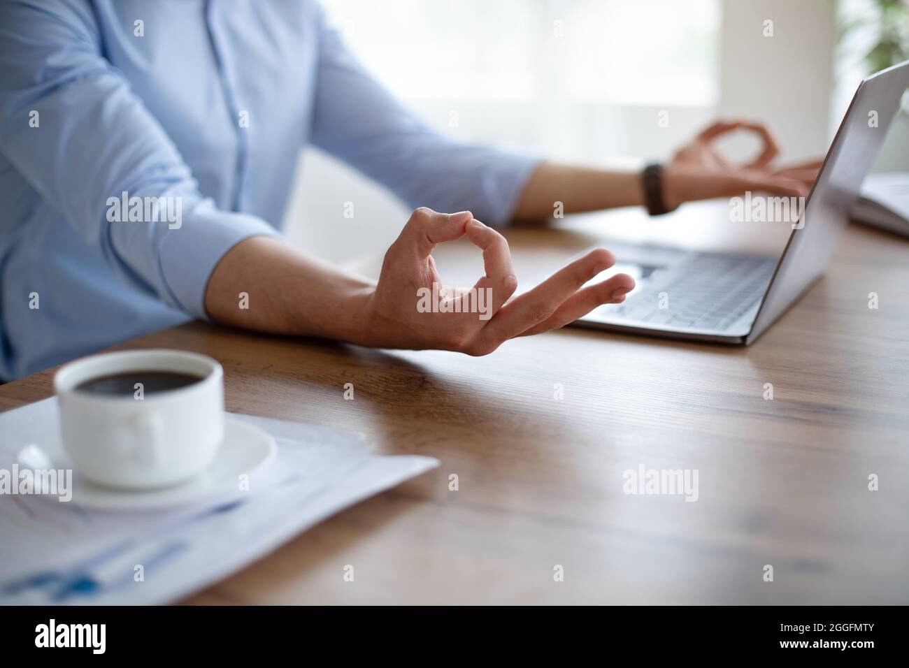 Ragazzo arabo irriconoscibile meditating davanti al PC portatile, rendendo gyan mudra con entrambe le mani, cercando di mantenere la calma sul posto di lavoro, primo piano. Gestione dello stress Foto Stock