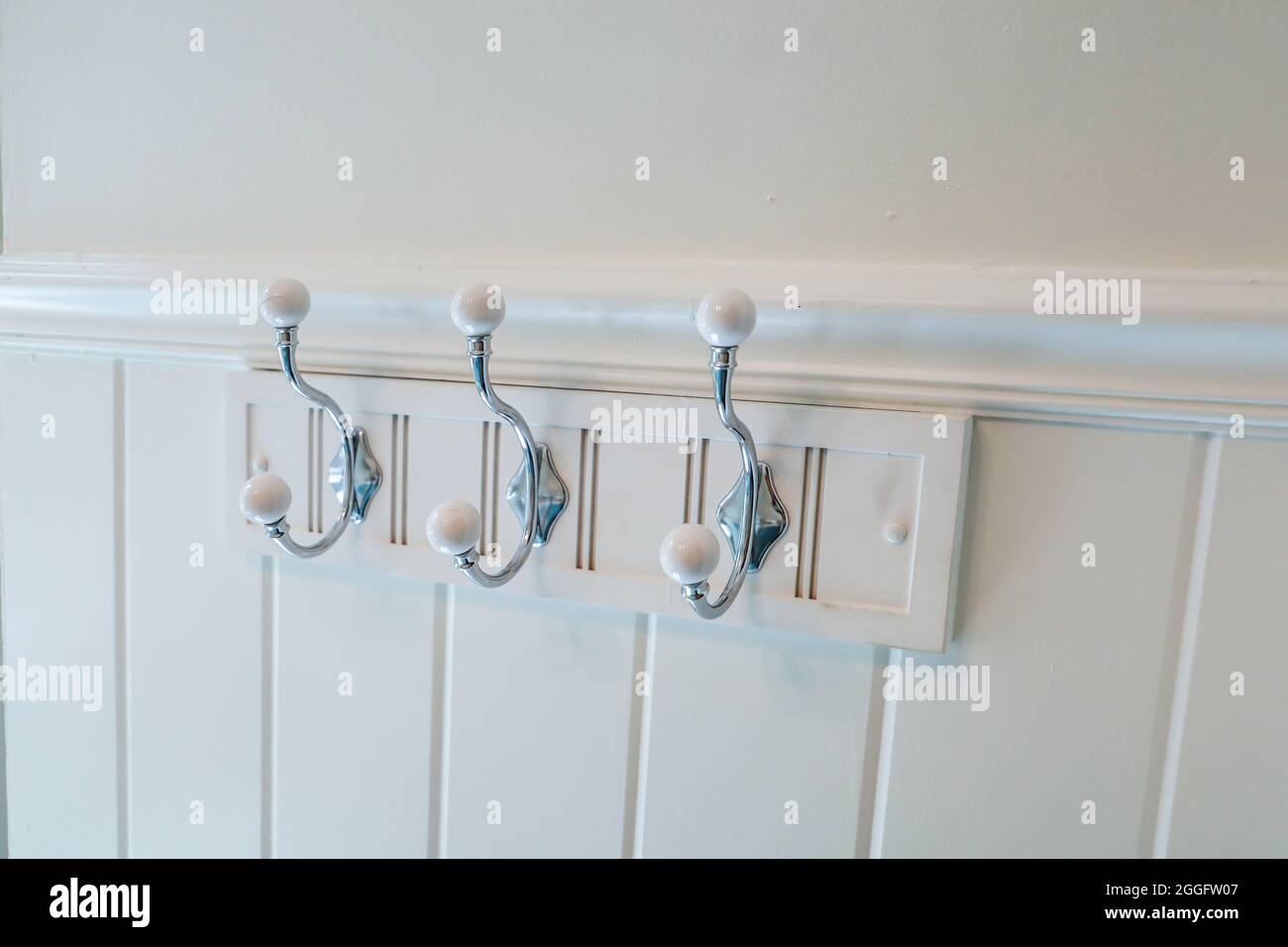 Una parete bianca del bagno con ganci per asciugamani Foto stock - Alamy