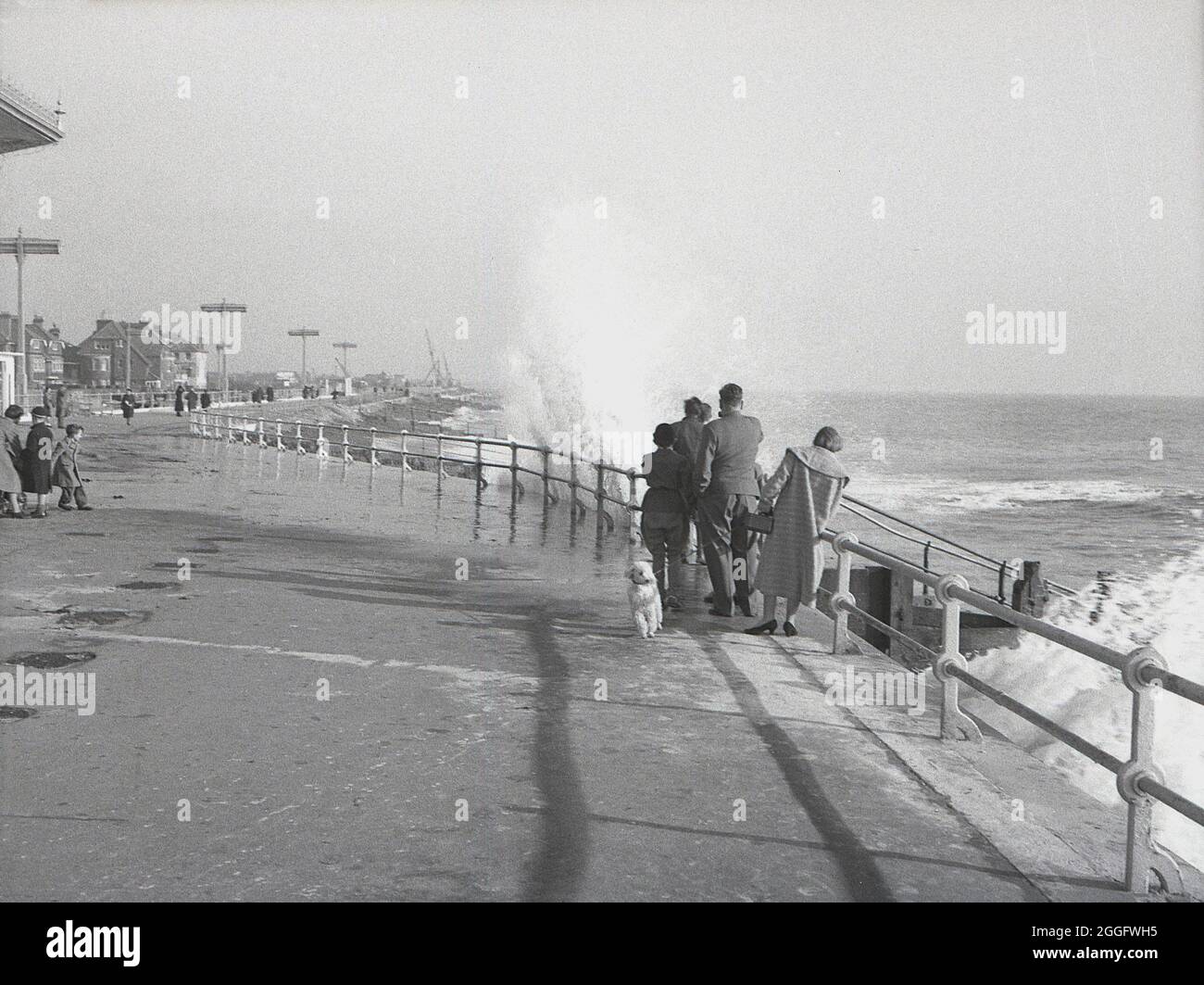 1950, storico, un famoso in piedi accanto alla ferrovia come le onde ha colpito il passaggio pedonale alla costa a Selsey, West Sussex, Inghilterra, Regno Unito. Foto Stock