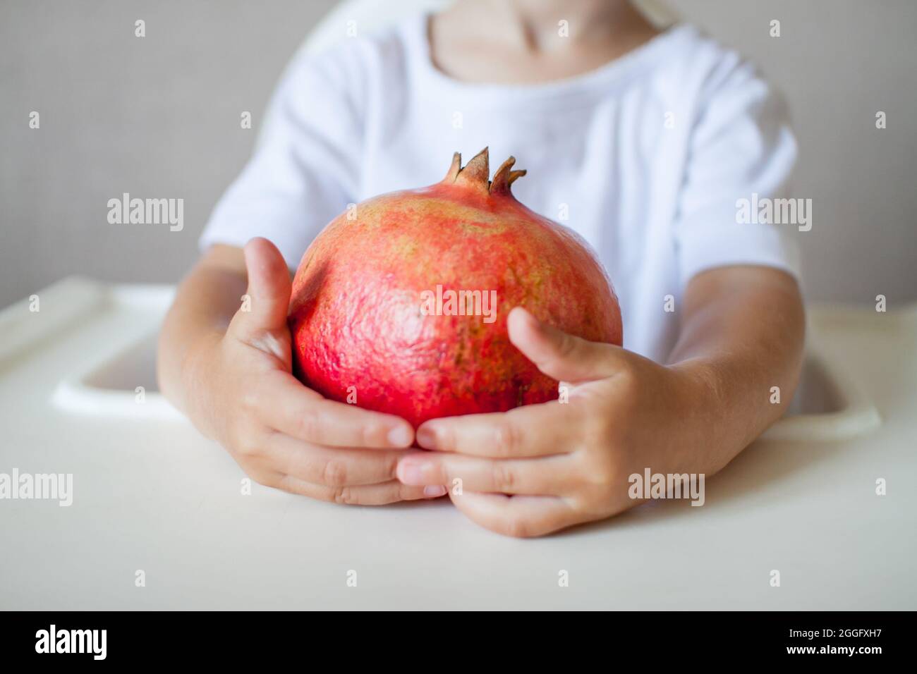 Pomegranate la frutta nelle mani di un bambino piccolo primo piano. Il simbolo del nuovo anno ebraico. Rosh Hashana. Foto Stock