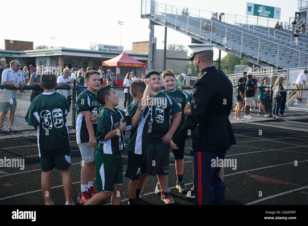 Brian Hubert, a destra, il comandante della Recruiting Station Cleveland, parla con i giocatori di calcio junior durante una partita di football delle scuole superiori a Westlake, Ohio, 27 agosto 2021. Hubert e un'altra Marina innalzarono i colori durante l'inno nazionale per onorare i 13 membri del servizio degli Stati Uniti uccisi a Kabul, in Afghanistan nell'agosto del 2021. (STATI UNITI Foto del corpo marino di CPL. Nello Miele) Foto Stock