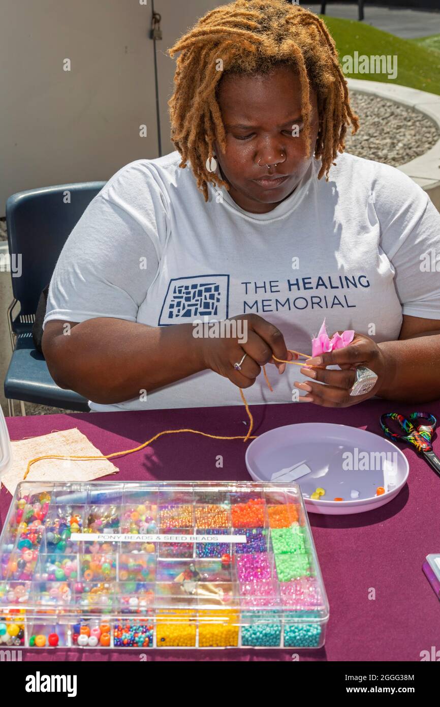 Detroit, Michigan, Stati Uniti. 31 ago 2021. Un memoriale per aiutare la comunità a guarire dalla pandemia covida è fatto a mano da centinaia di residenti della zona di Detroit. Il Memoriale di guarigione è costituito da sacche colorate in tessuto contenenti messaggi scritti a mano su persone care perdute. Ebiyemi Kweli dimostra come realizzare le buste. Il monumento sarà in mostra per un anno presso il centro convegni TCF della città. Credit: Jim West/Alamy Live News Foto Stock