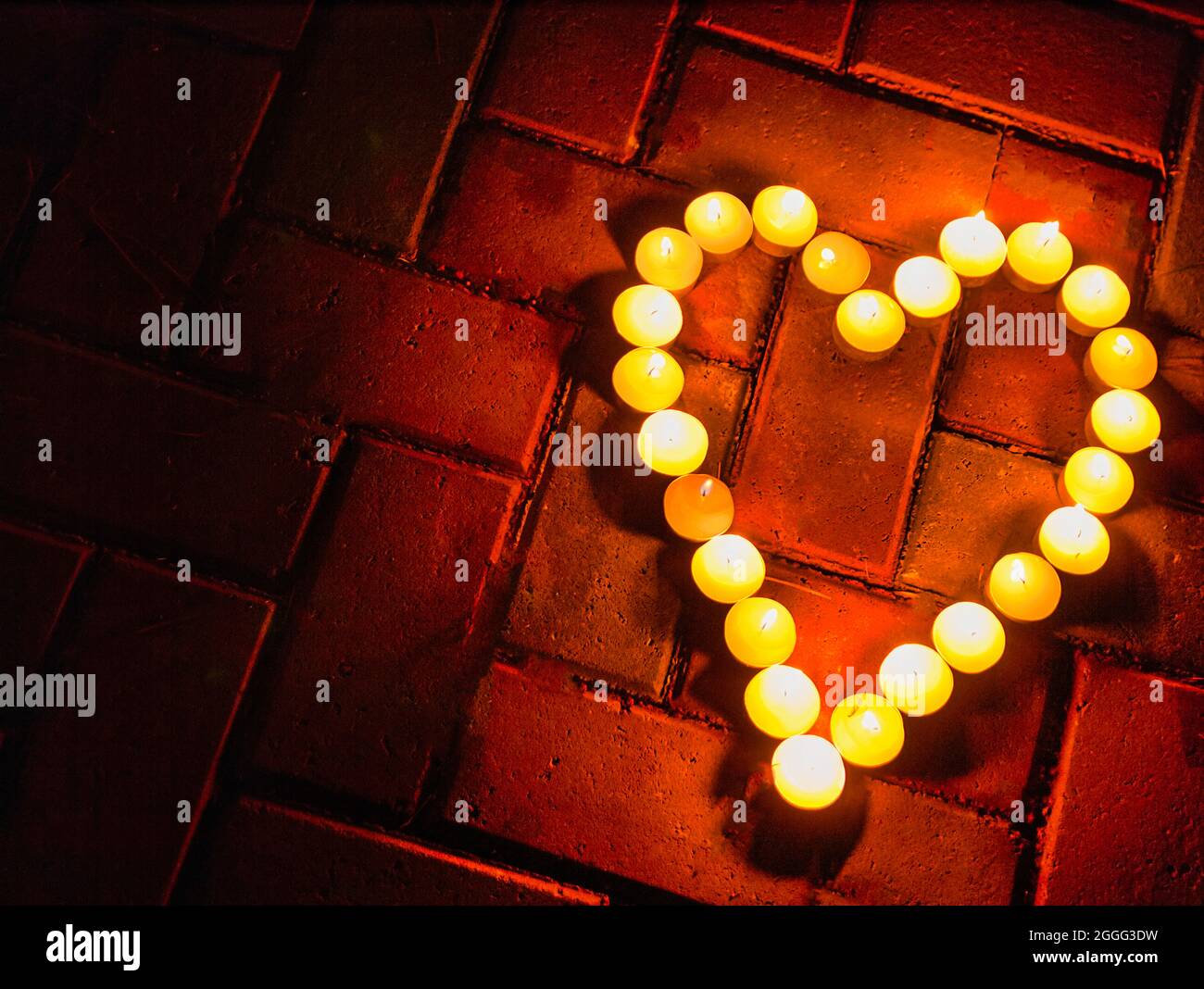 Shot di candele brucianti a forma di cuore su uno sfondo di mattoni. Foto Stock