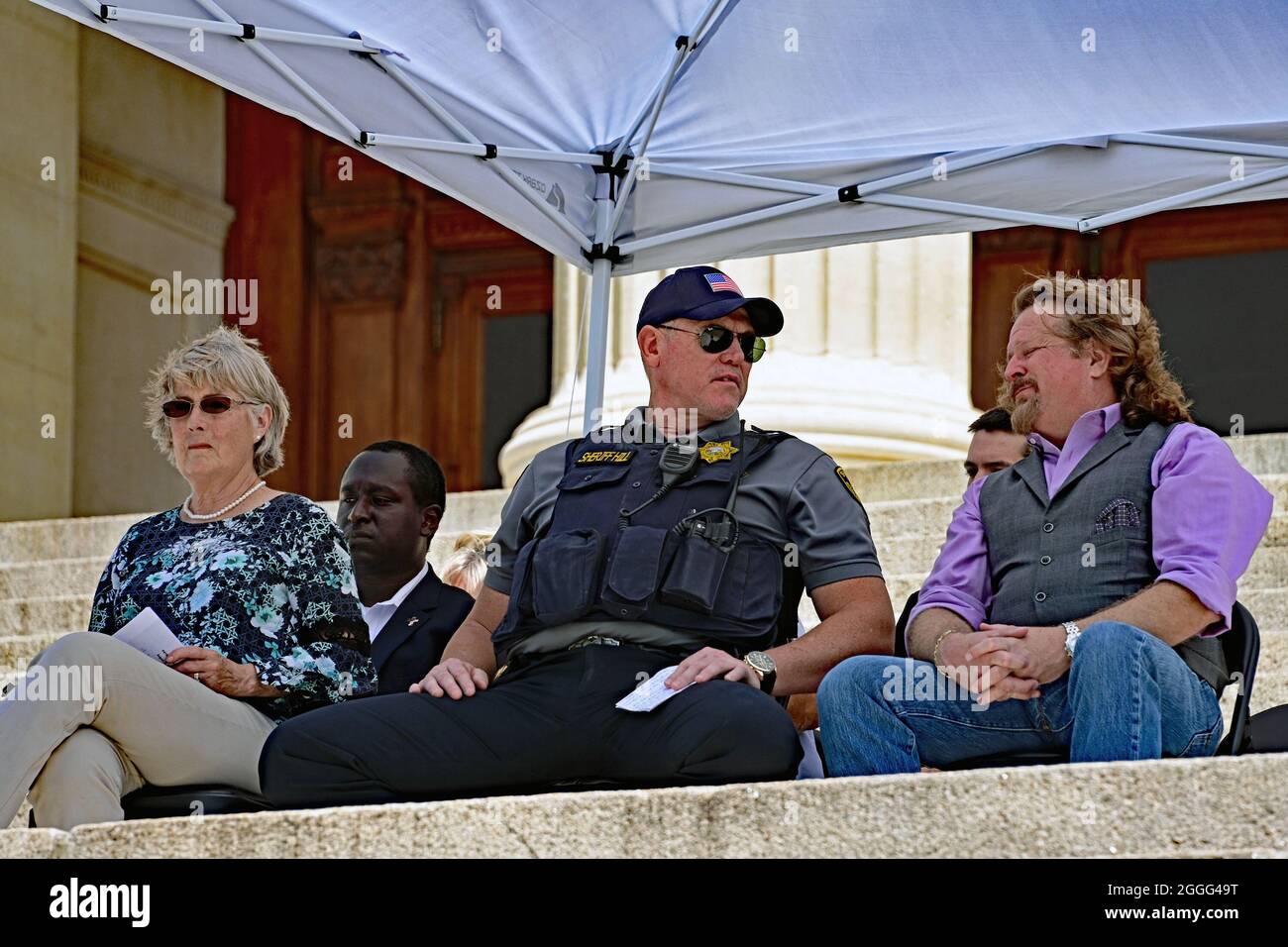 Yopeka, KS, USA. 28 agosto 2021. La presidente del partito repubblicano della contea di Lione Peggy Mast, lo sceriffo della contea di Shawnee Brian Hill, l'ospite del talk show radiofonico Jim Price e il candidato del tesoriere dello stato Michael Austin siedono sotto un baldacchino mentre attendono di affrontare il Kansas Patriots Freedom Rally fuori del palazzo del campidoglio. Agosto 28, 2021. Credit: Mark Reinstein/Media Punch/Alamy Live News Foto Stock