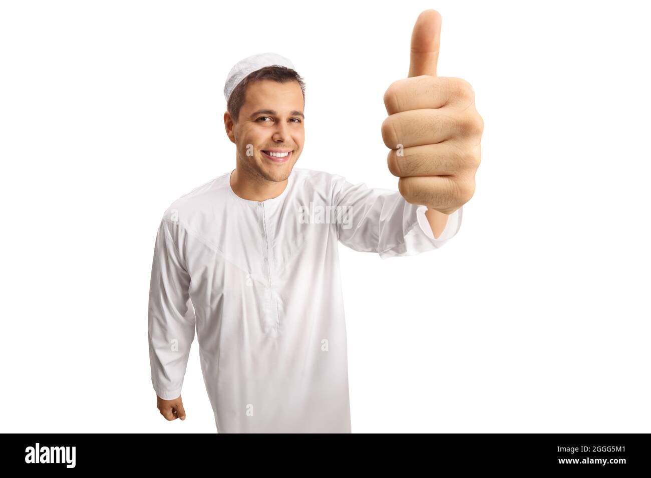Giovane uomo allegro in abiti etnici bianchi che mostrano i pollici di fronte alla macchina fotografica isolata su sfondo bianco Foto Stock