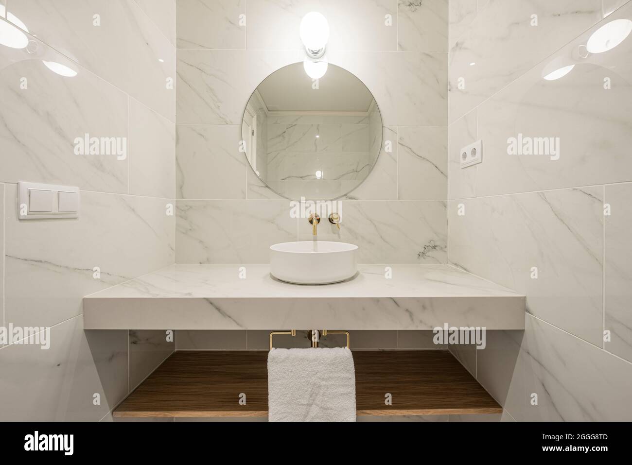 vista frontale del lavello in marmo bianco e del piano di lavoro con vene grigie e rubinetti in oro Foto Stock