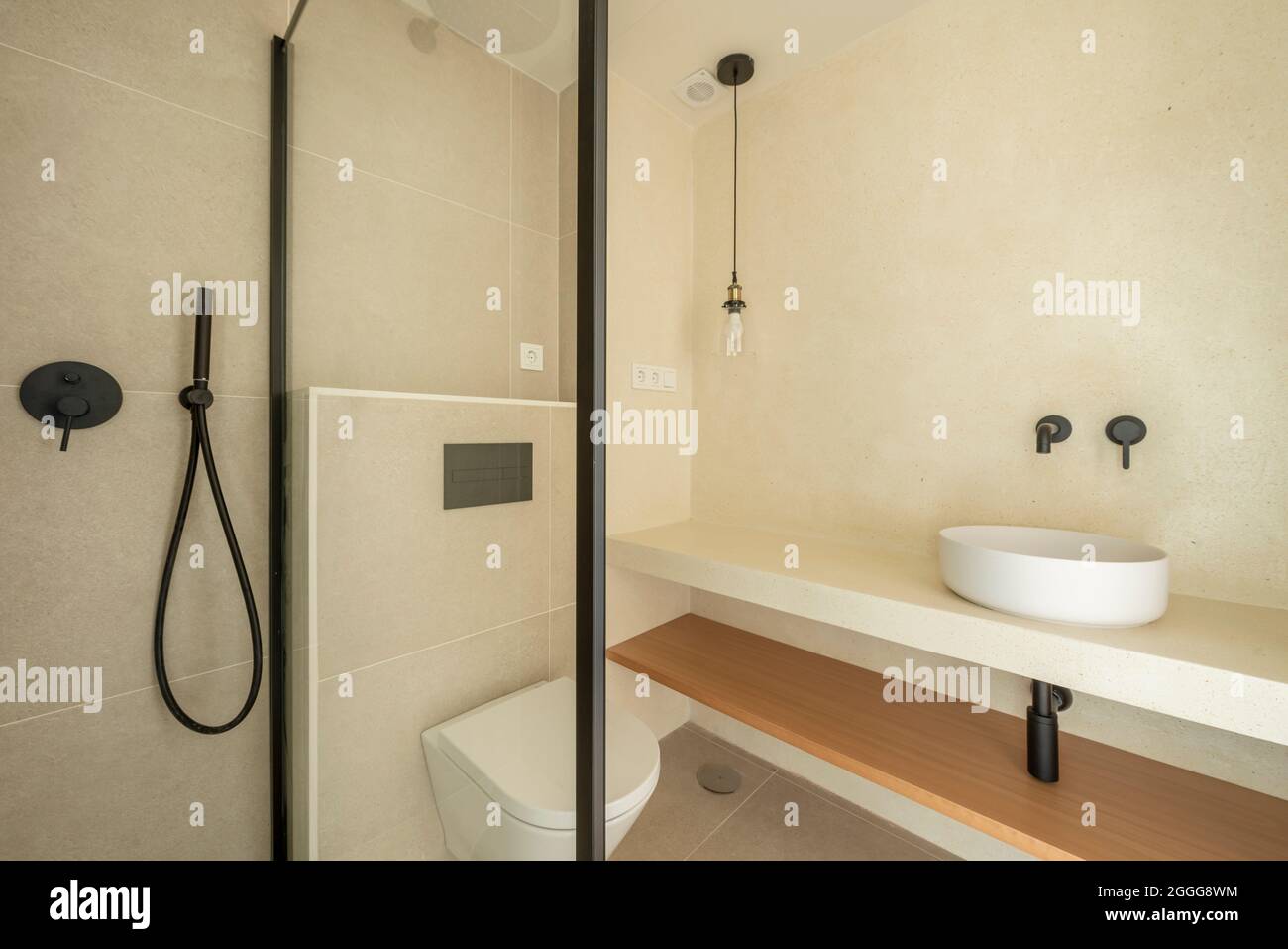 WC con doccia con piano di appoggio e lavandino minimalista in tonalità  chiare e accessori neri Foto stock - Alamy