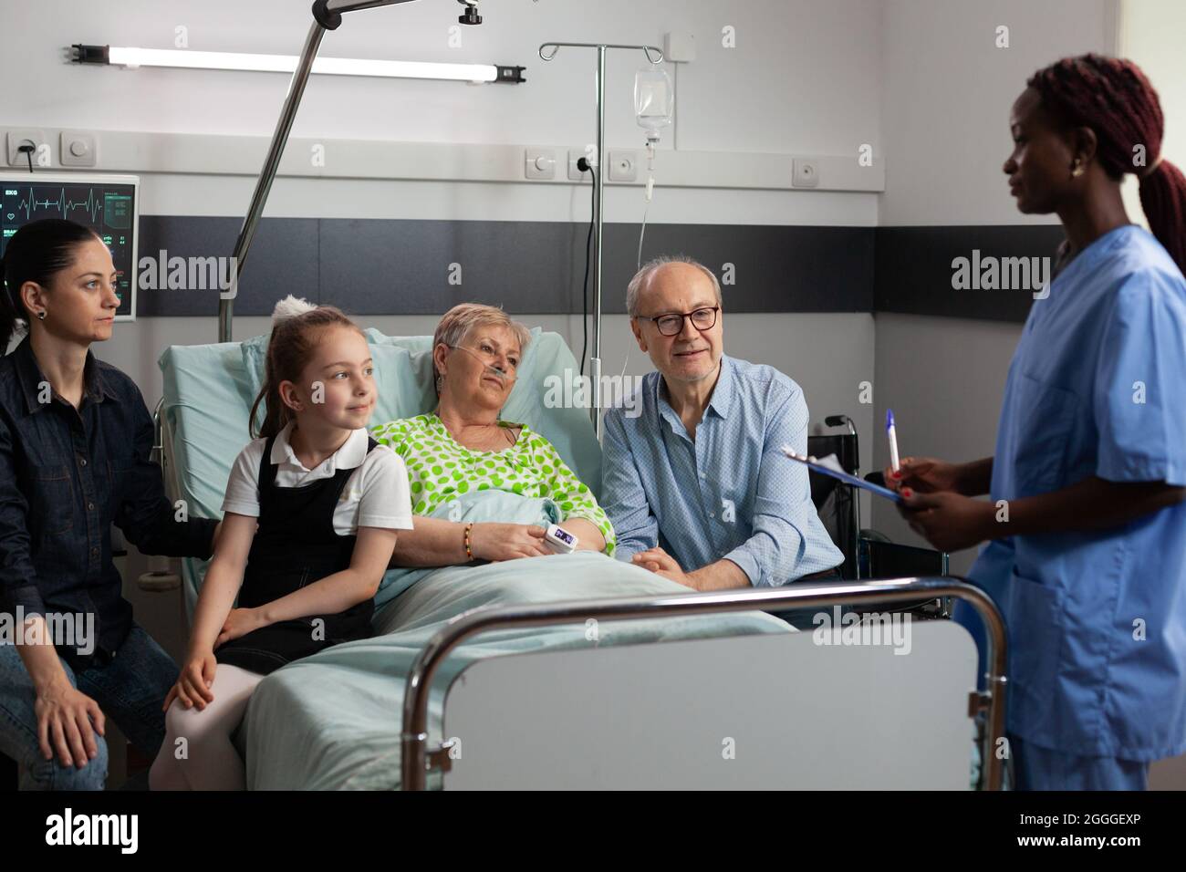 Infermiera afroamericana che parla di sintomi di malattia con anziana anziana anziana malata in reparto ospedaliero. Famiglia allegra in visita paziente in pensione che la sostiene durante il recupero clinico. Terapia medica Foto Stock