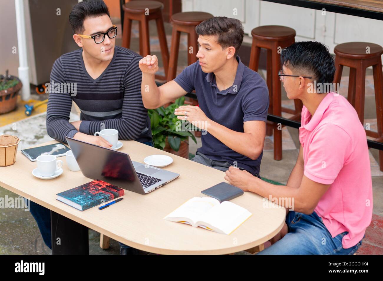 tre studenti che chiacchierano in una caffetteria all'aperto in stile latino Foto Stock