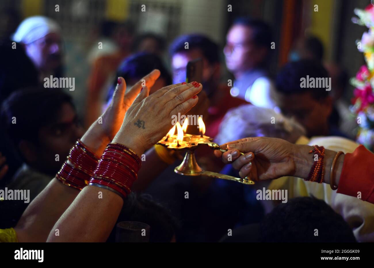 I devoti indù indiani si uniscono alle loro mani in preghiera mentre si trovano davanti a una statua del Dio indù Krishna, al Tempio di Jabalpur, Foto Stock