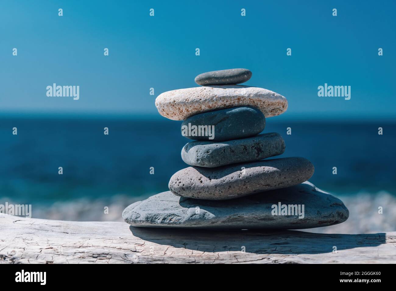 Equilibrata piramide di ciottoli sulla spiaggia in una giornata di sole. Abstract Sea bokeh sullo sfondo. Messa a fuoco selettiva. Pietre Zen sulla spiaggia di mare, meditazione Foto Stock