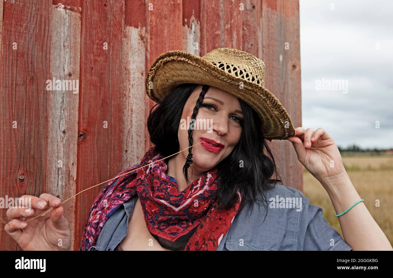 Umea, Norrland Svezia - 21 agosto 2021: cowgirl al granaio rosso in campo Foto Stock